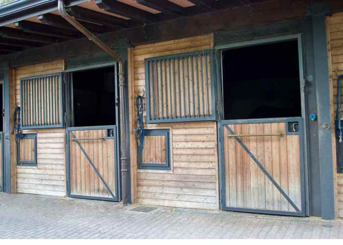 A row of wooden stables with their doors open