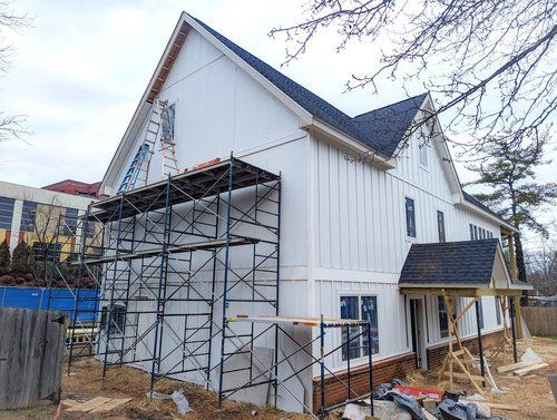 A large white house is being built with scaffolding around it.