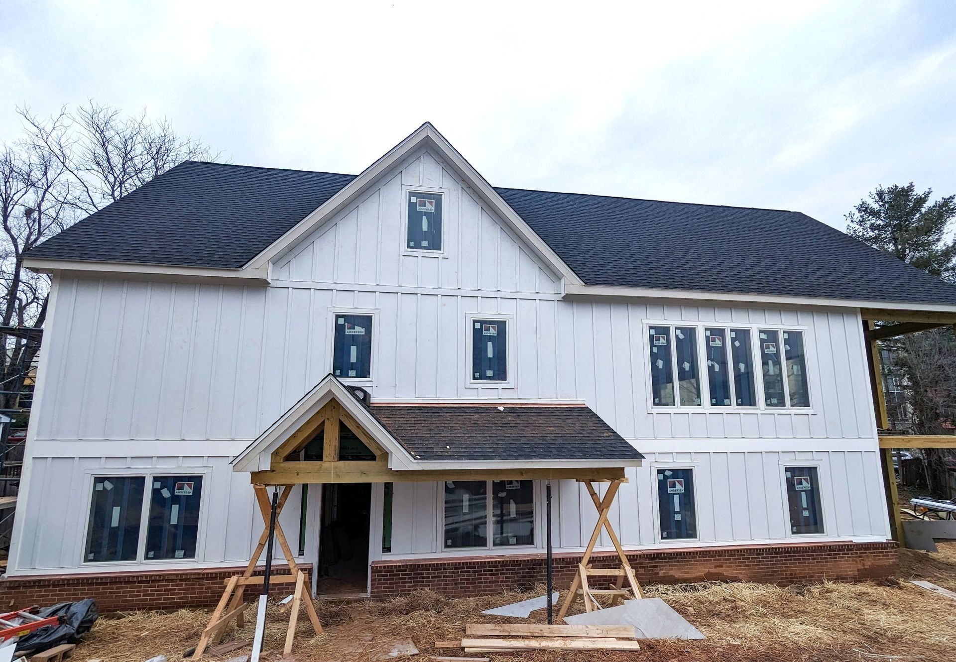 A large white house with a black roof is being built.