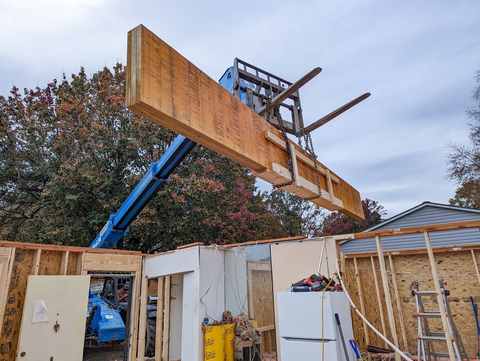 A forklift is lifting a large piece of wood into a house.