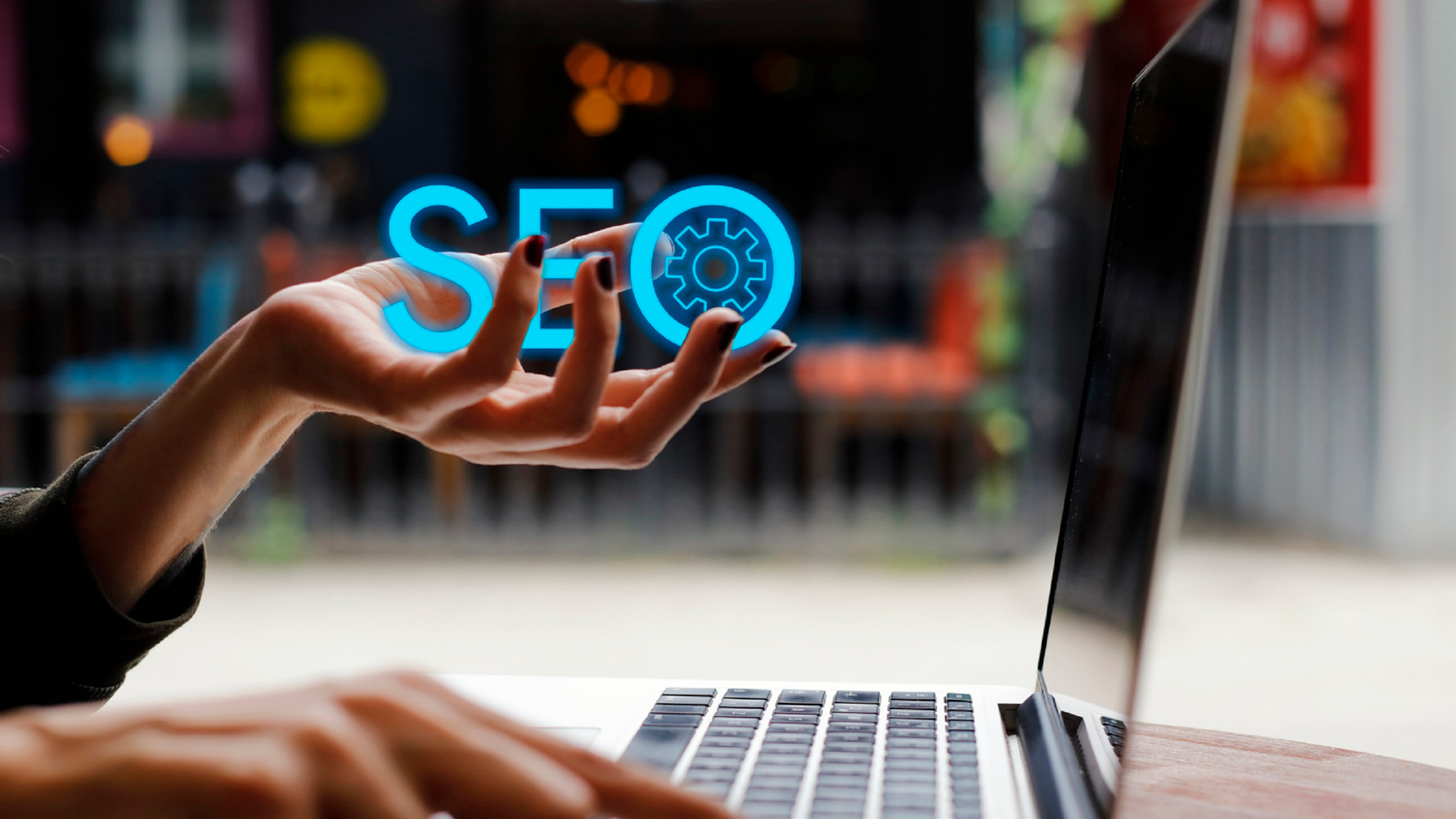 Woman's hand hovering over a laptop, with the neon word