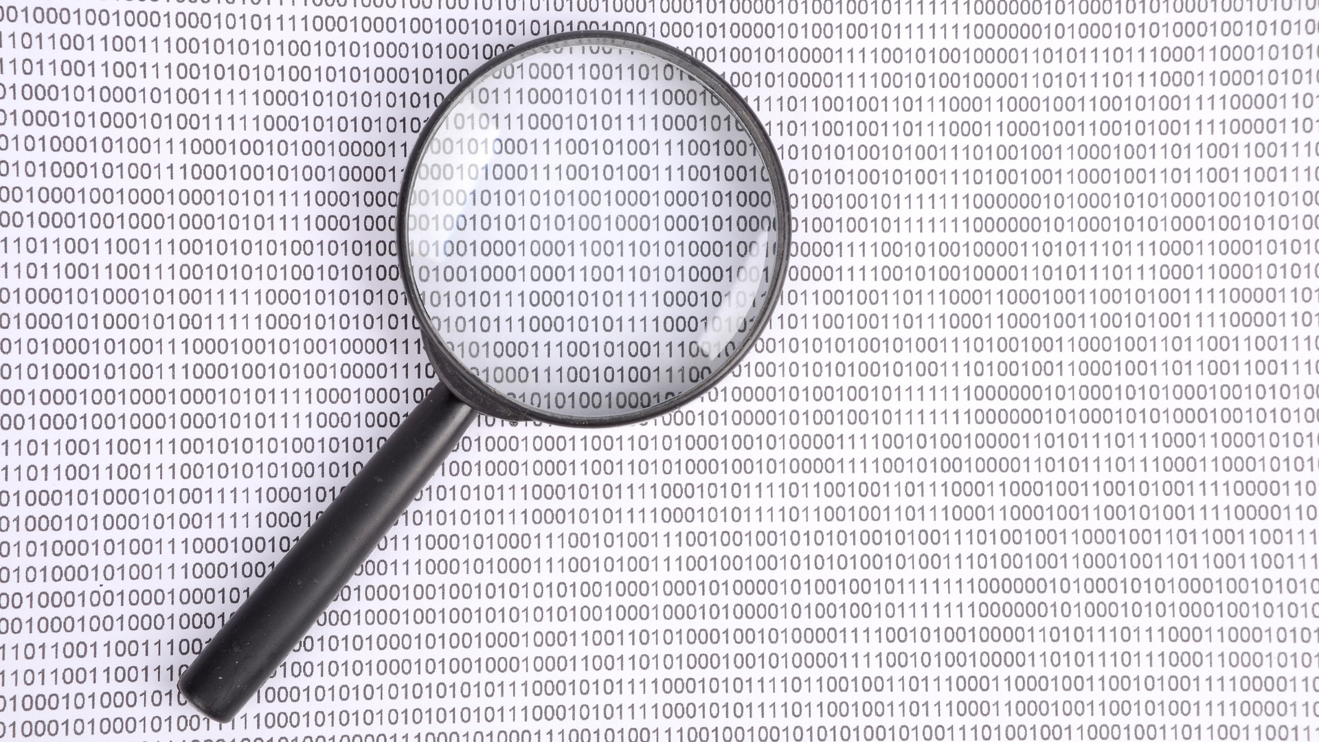 Magnifying glass over a white background of binary code.
