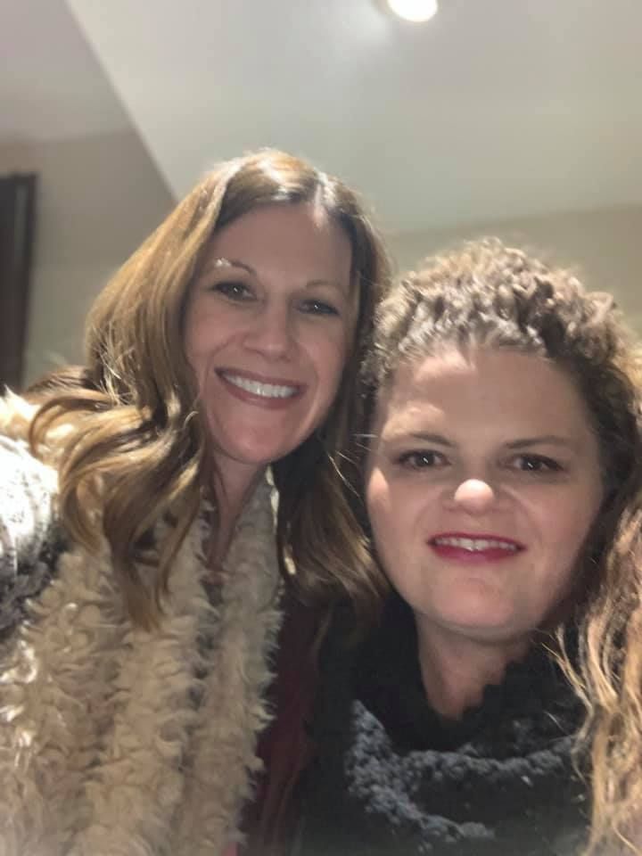 Two women are posing for a picture together and smiling for the camera.