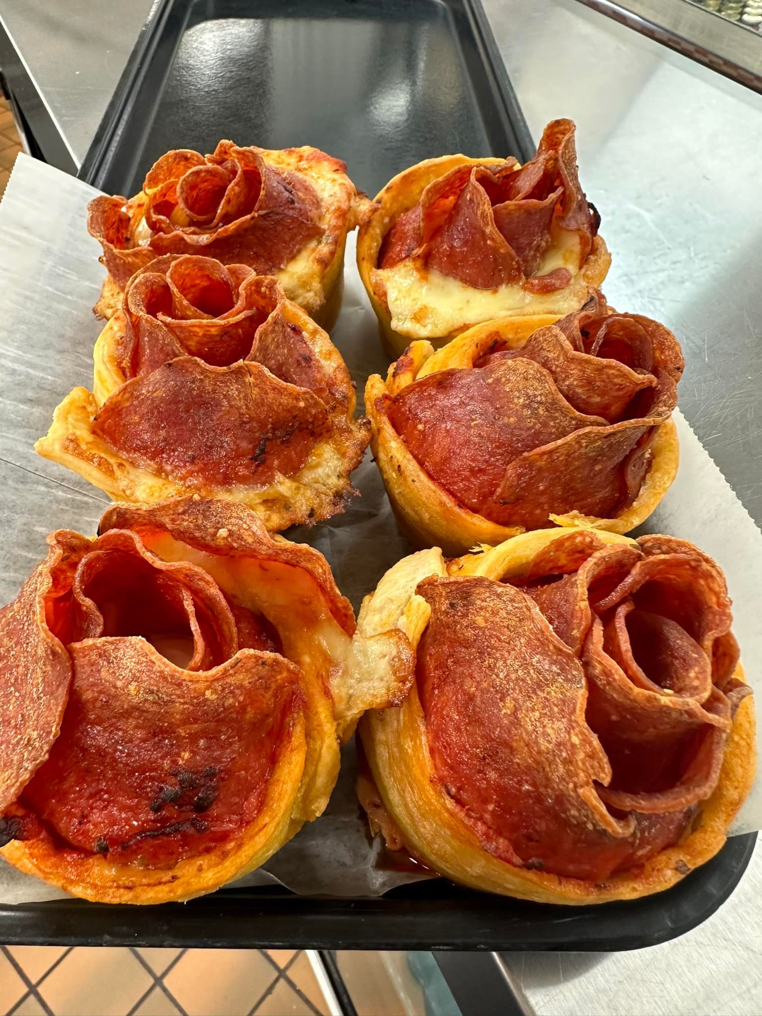 A tray of pepperoni pizza cups shaped like roses.