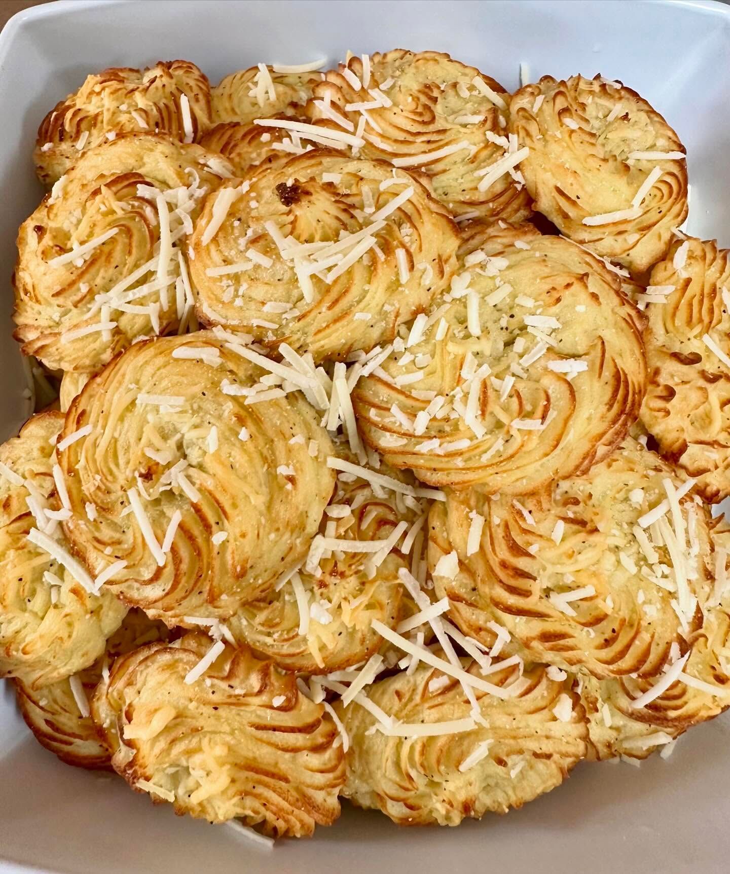 A white bowl filled with potato puffs with cheese on top.