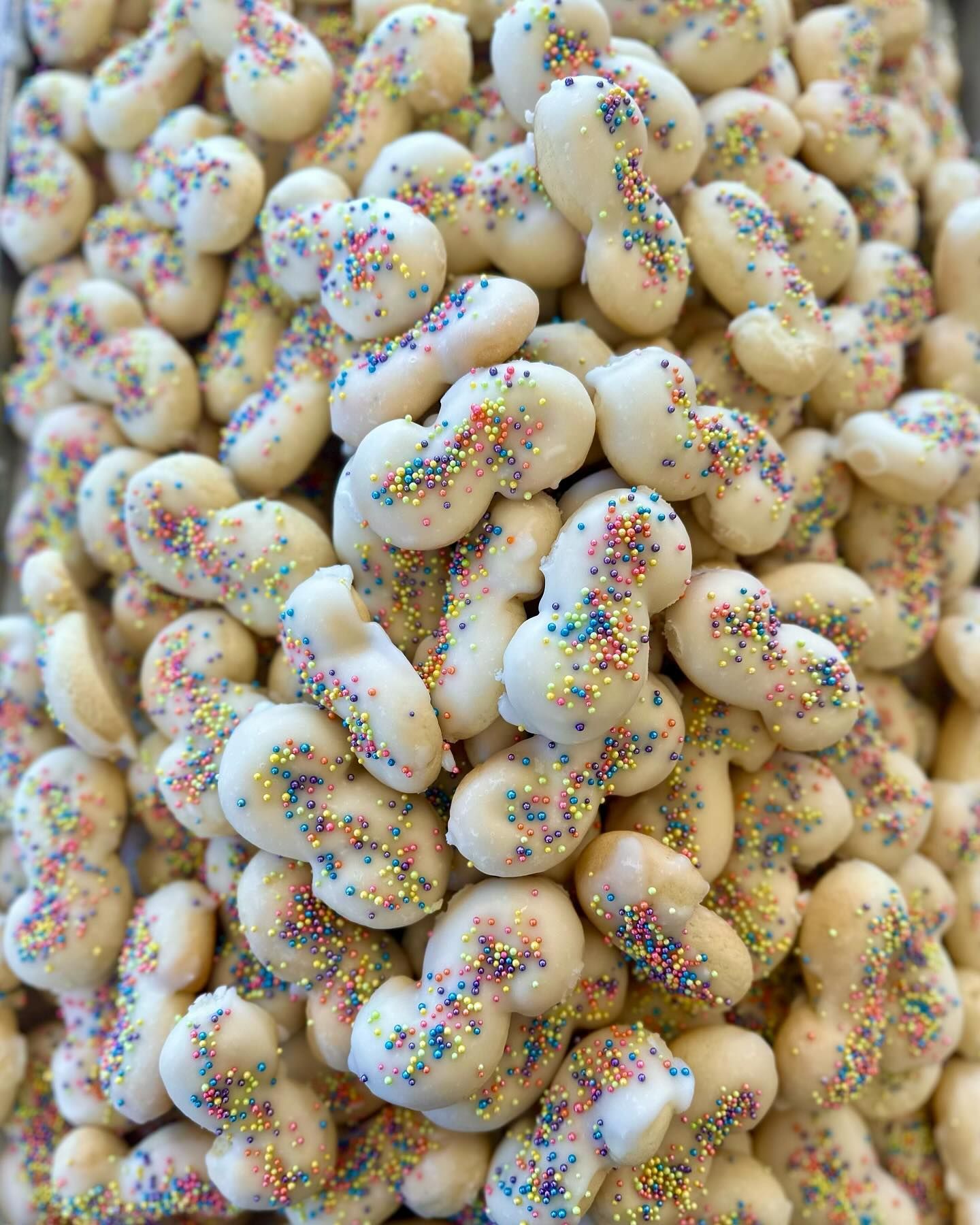 A pile of white cookies with sprinkles on them.