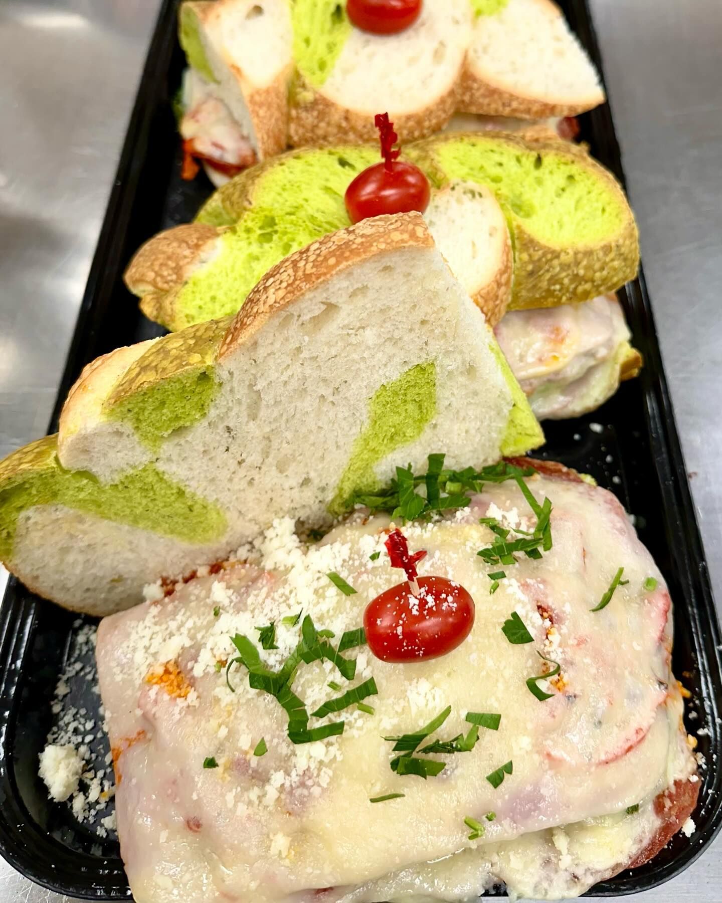 A close up of a tray of sandwiches with a cherry on top.