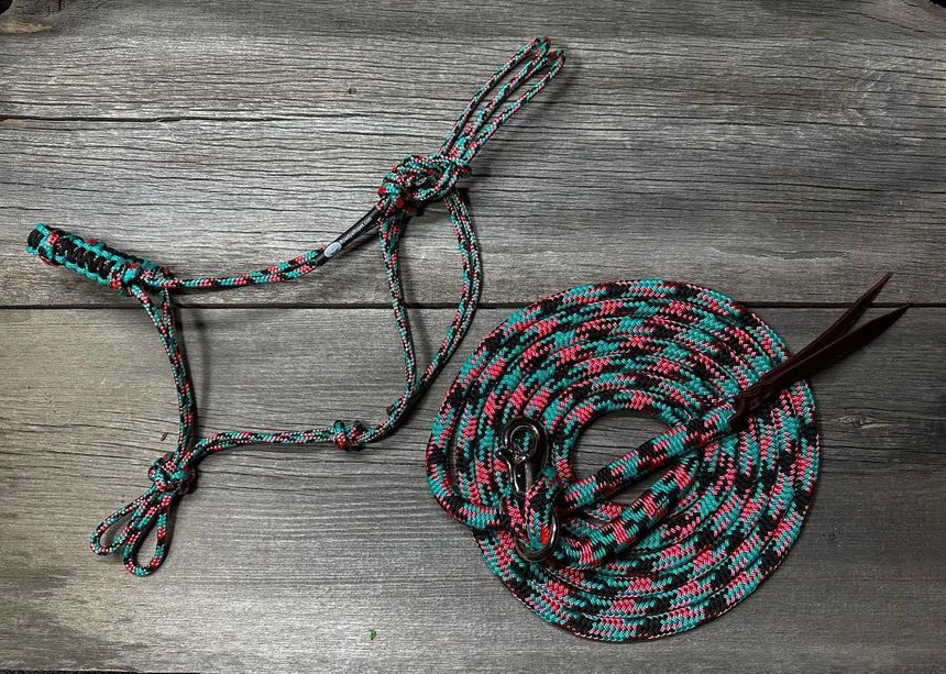 Braided red, black, and turquoise cord wound into a coil, with a looped handle on a wooden surface