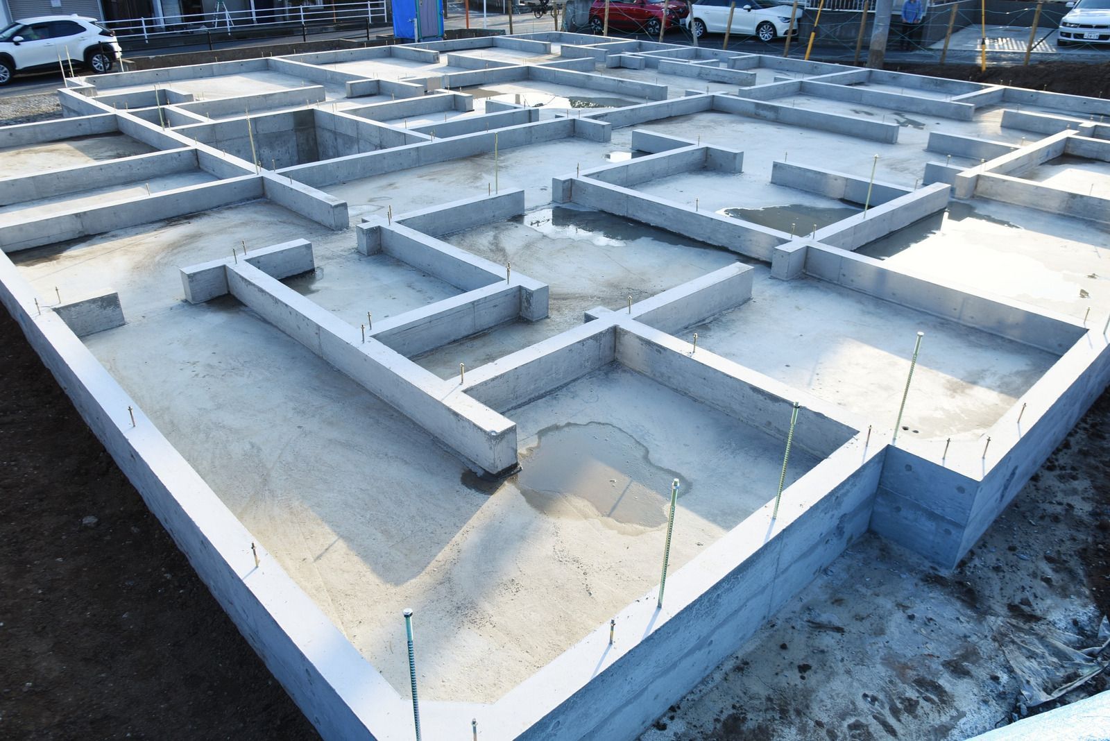Wet concrete pouring from a truck chute onto a construction site, forming a gravelly slab surface