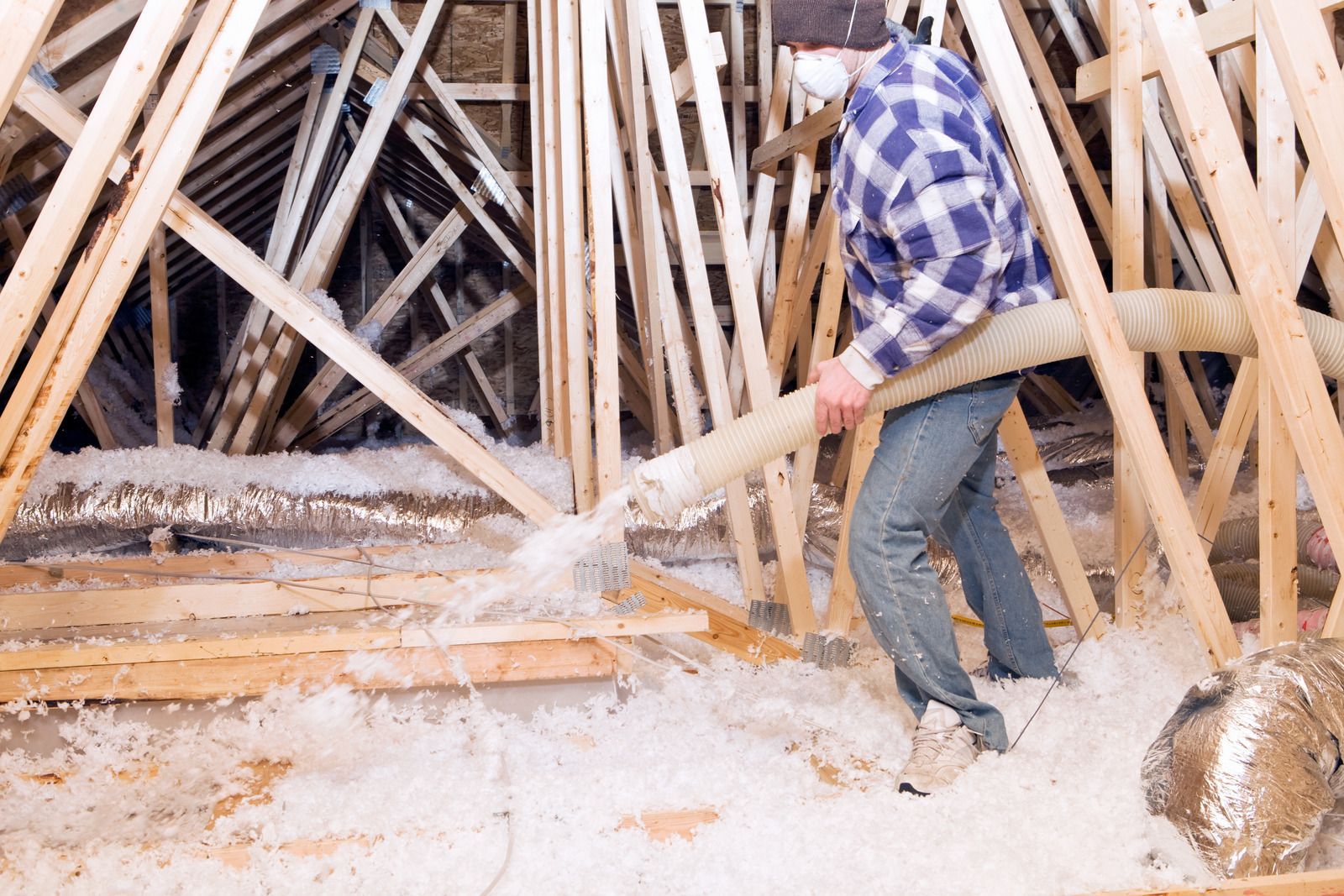 Person using a sledgehammer to break wooden beams in a dusty attic or construction area
