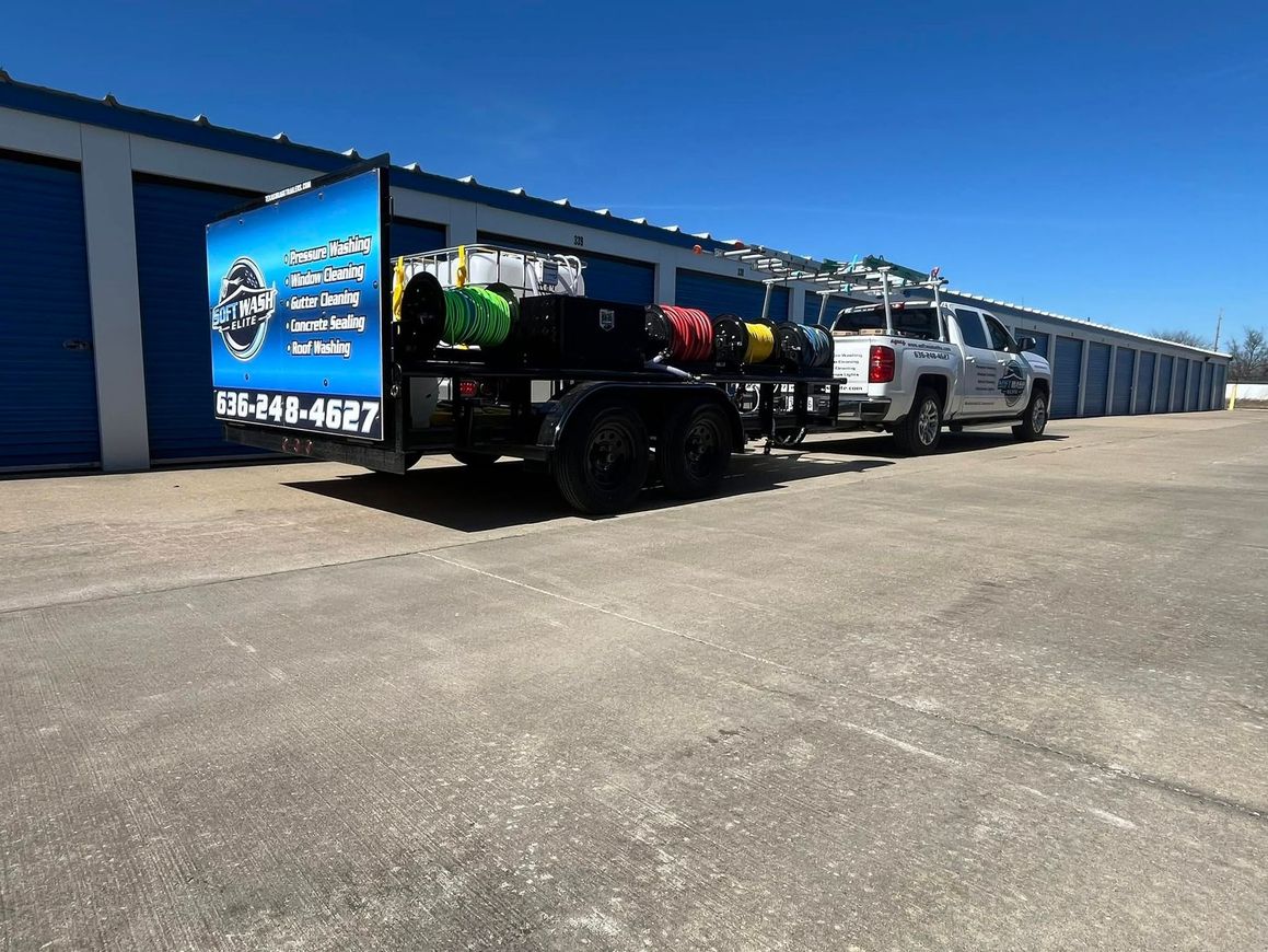 Truck and trailer parked beside blue storage units under a clear sky