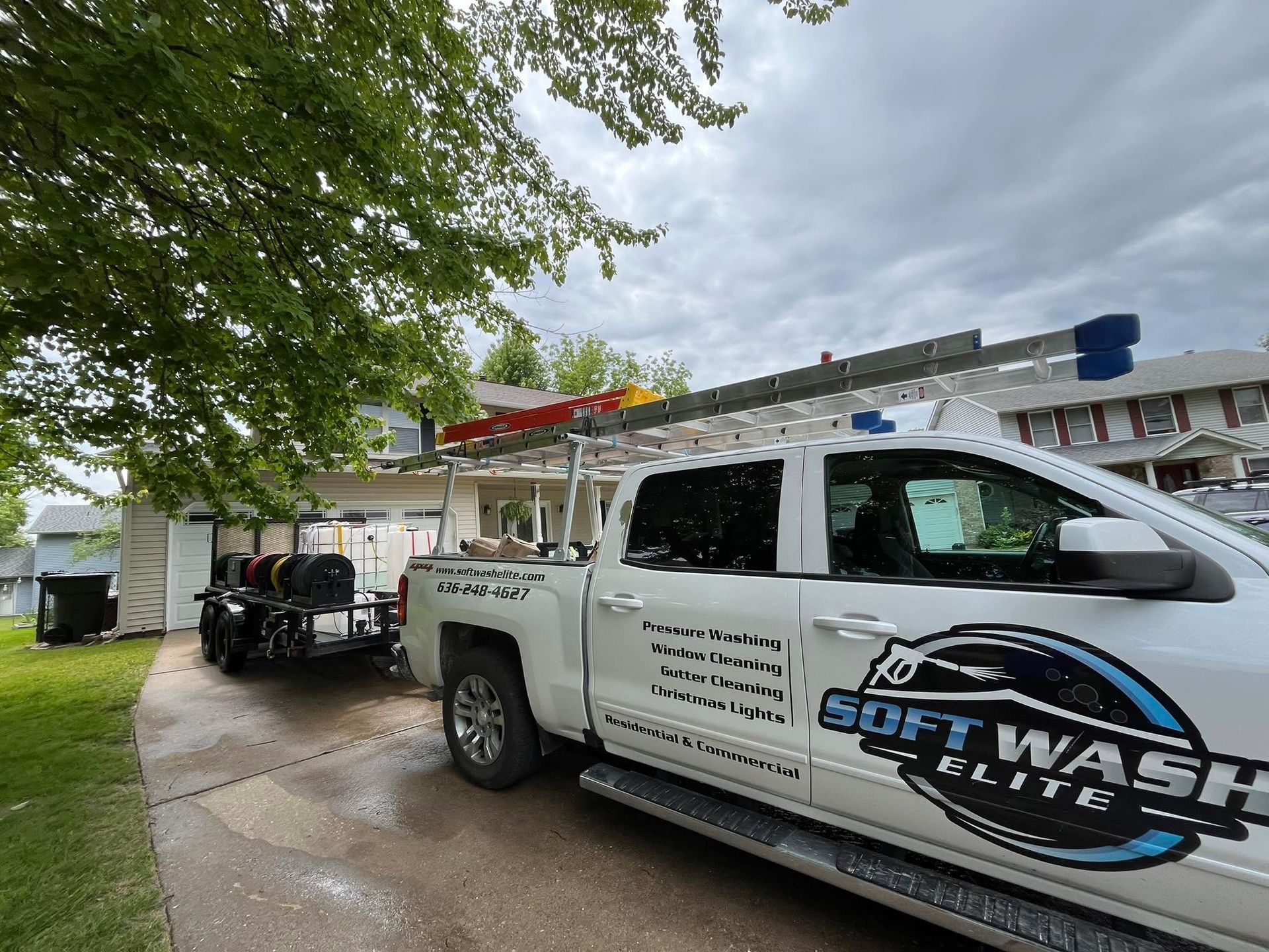 Two white SoftWash Elite trucks parked outside a building under cloudy skies