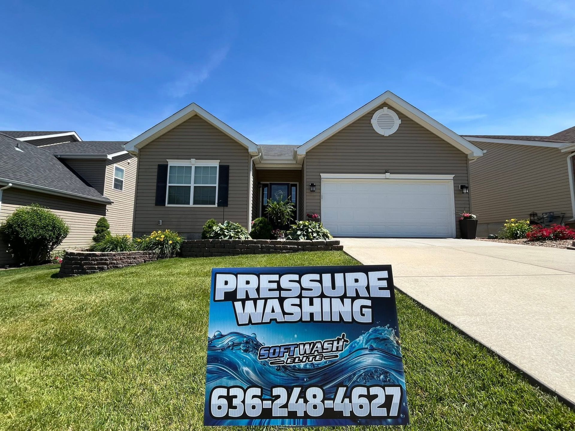 Pressure washing yard sign in front of a suburban house with a white garage and blue sky