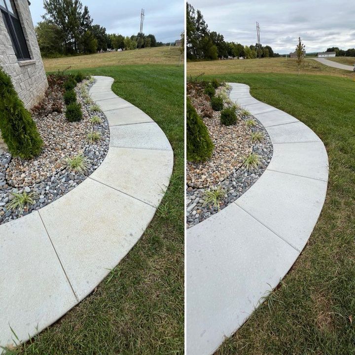 Curved white concrete walkway bordering a grassy yard and landscaping beside a house