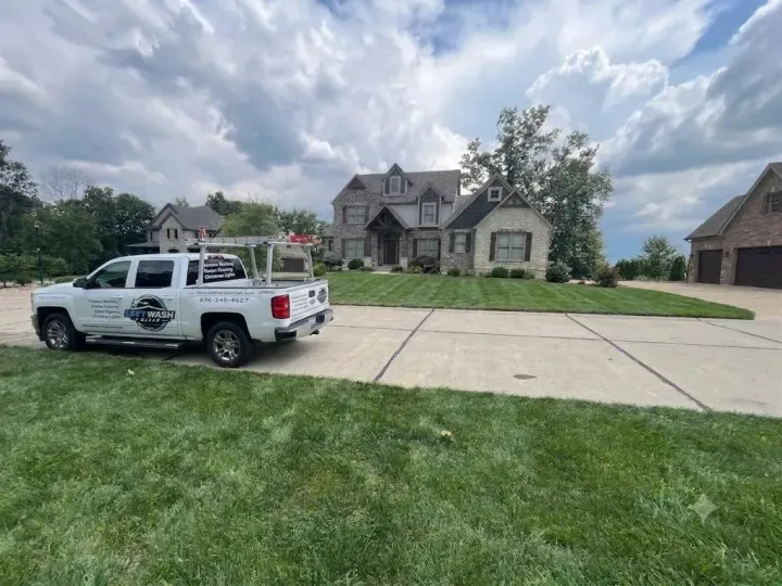 White pickup truck parked in front of a large stone house under a cloudy sky