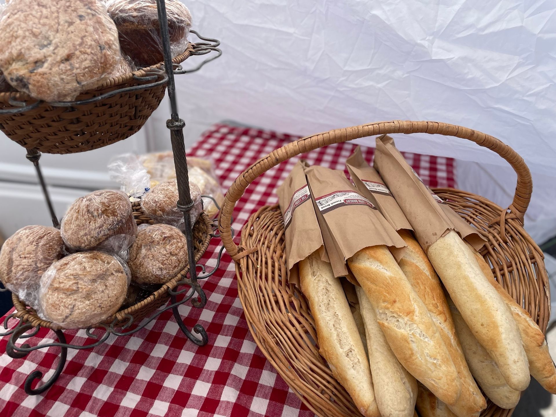A basket of bread sits on a checkered table cloth