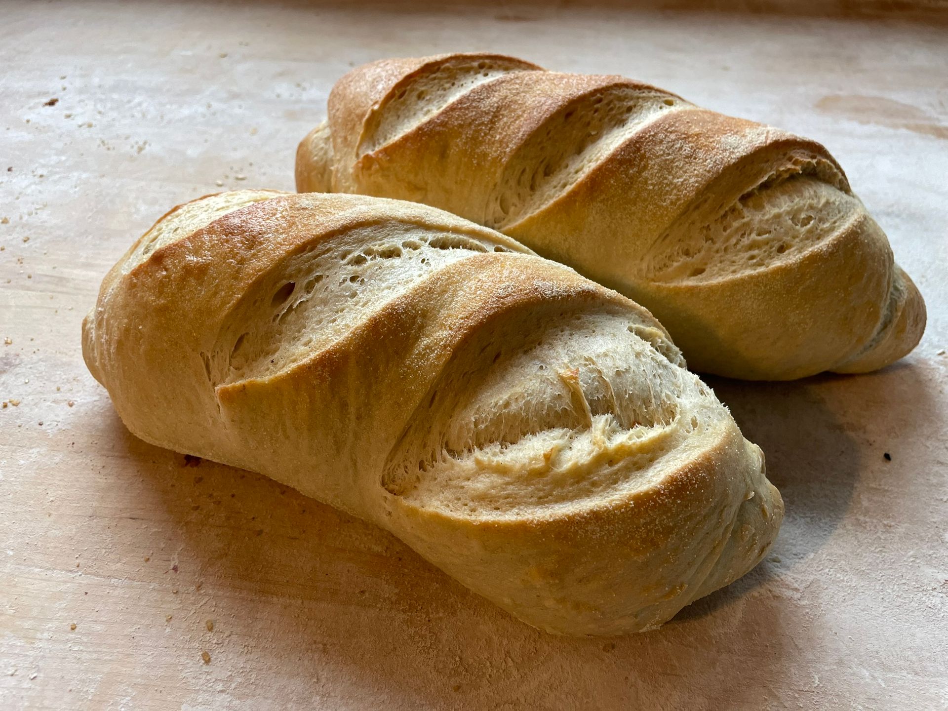 Two loaves of bread are sitting on a wooden table.