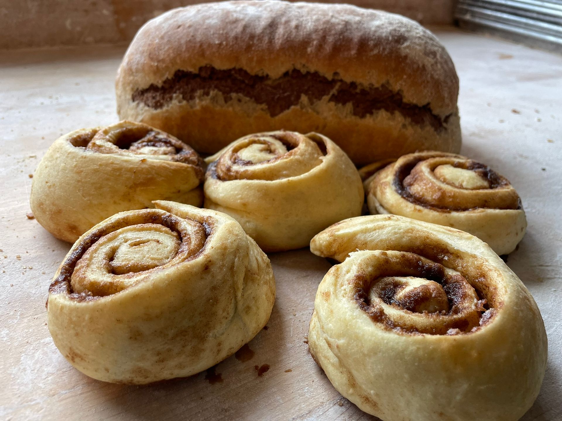 A bunch of cinnamon rolls and a loaf of bread on a table