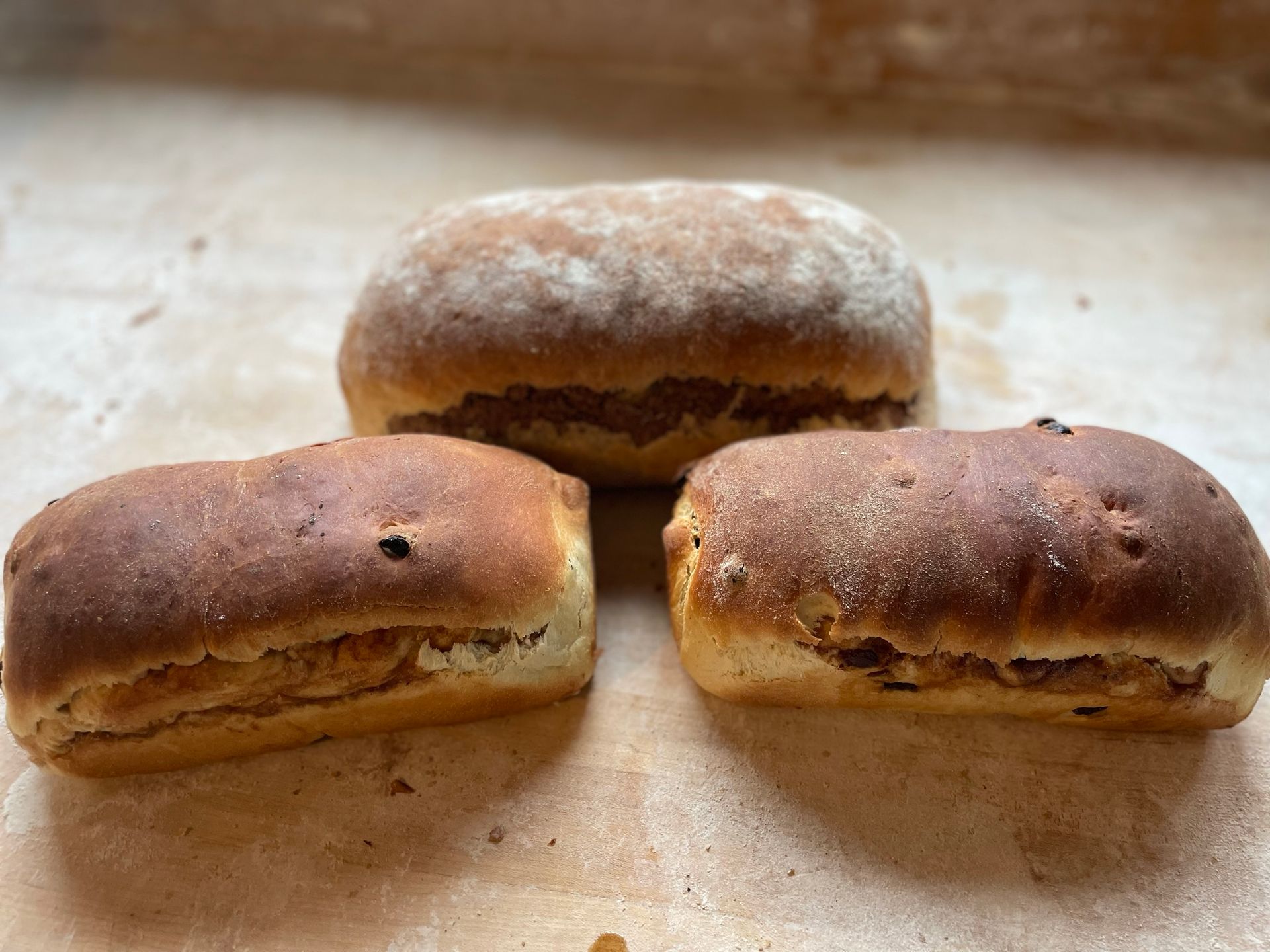 Three loaves of bread are sitting on a wooden table.
