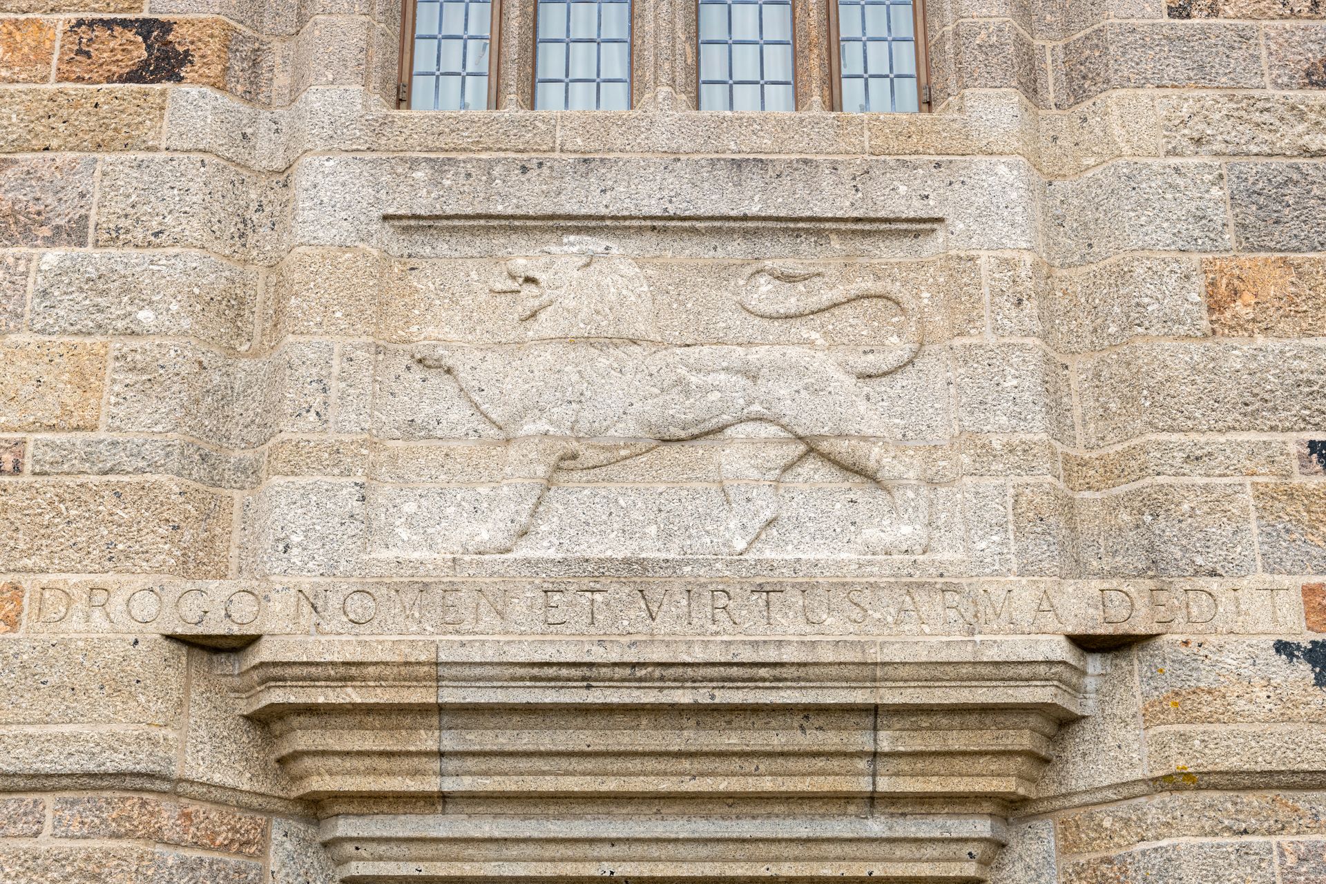Stone relief of a lion on a historic building facade beneath small windows
