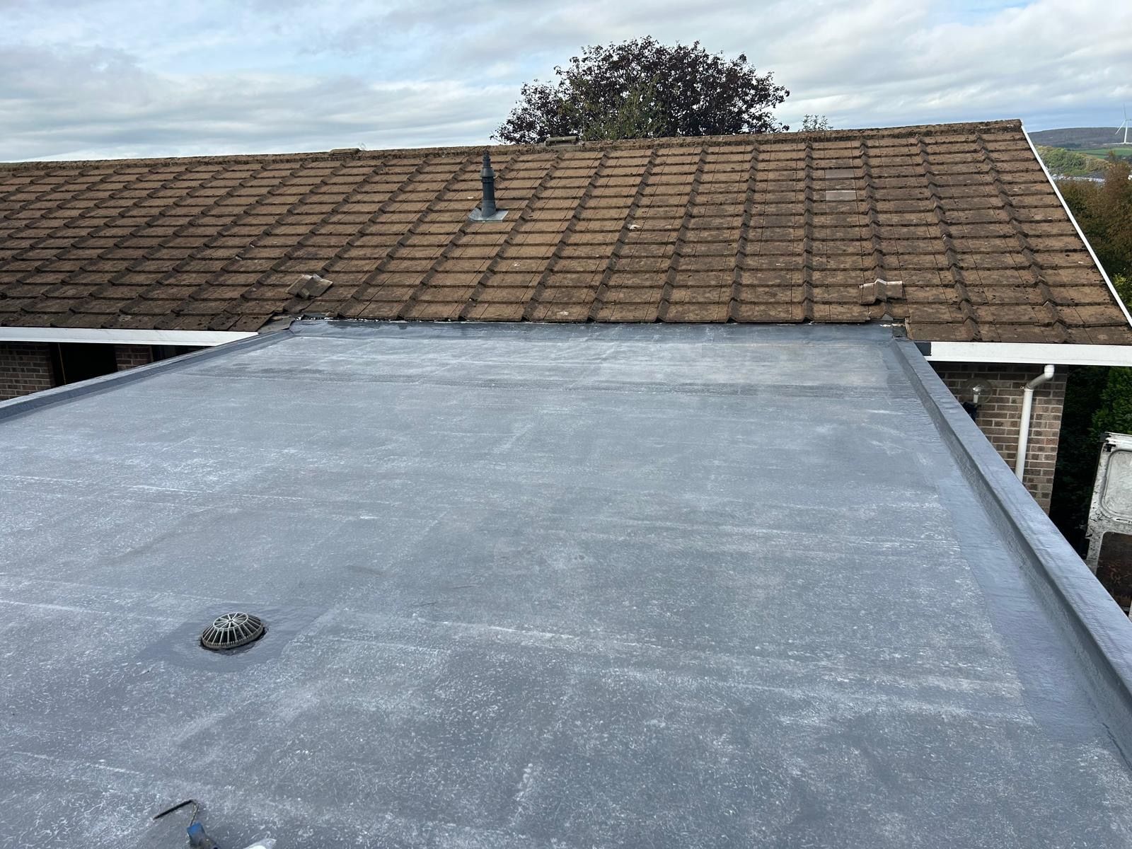 Completed grey flat roof adjoining an existing tiled roof