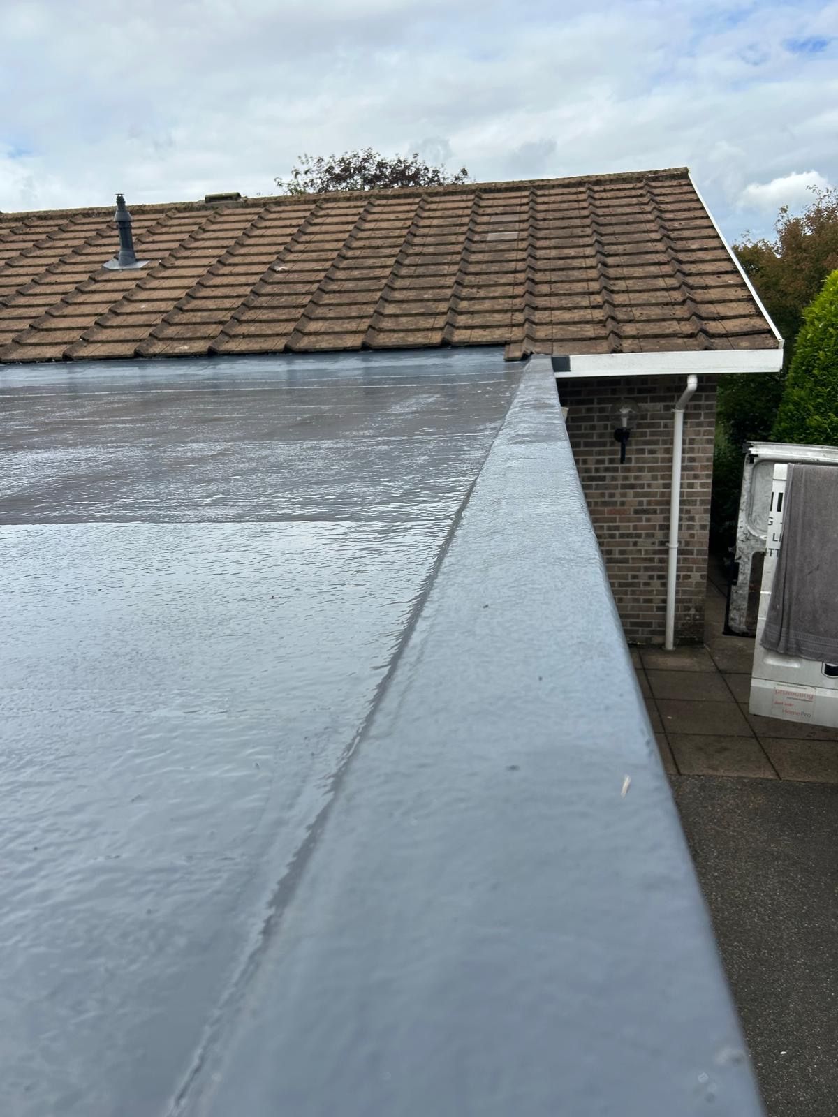 Grey flat roof with raised edge detailing alongside a tiled roof