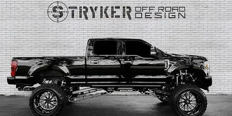 Black truck with custom suspension and wheels in front of a brick wall. Stryker Off Road Design logo.