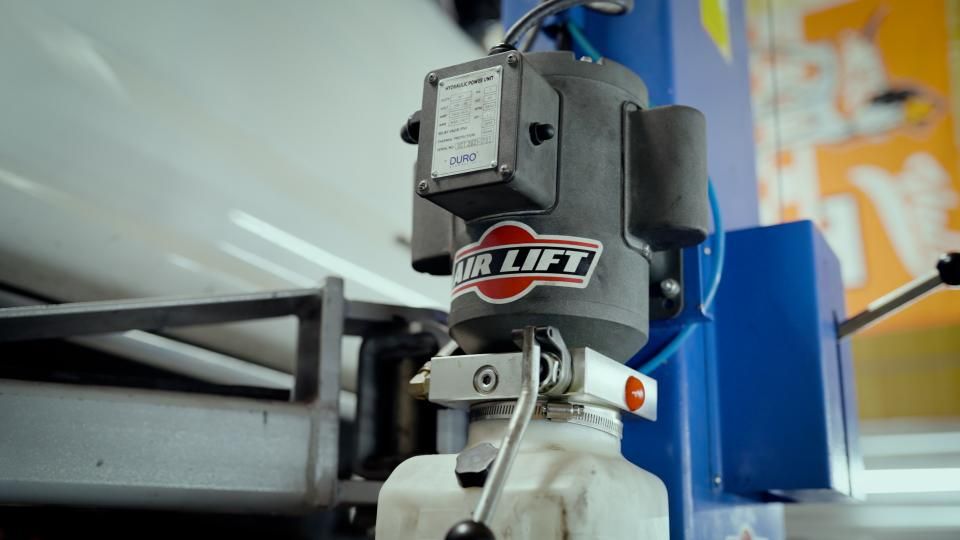 Close-up of a black and silver industrial machine mounted on white equipment in a workshop.
