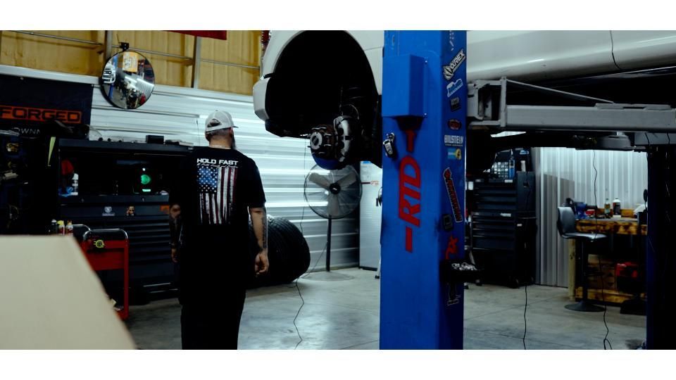 Auto repair shop with a car lifted on a hoist and a mechanic standing nearby