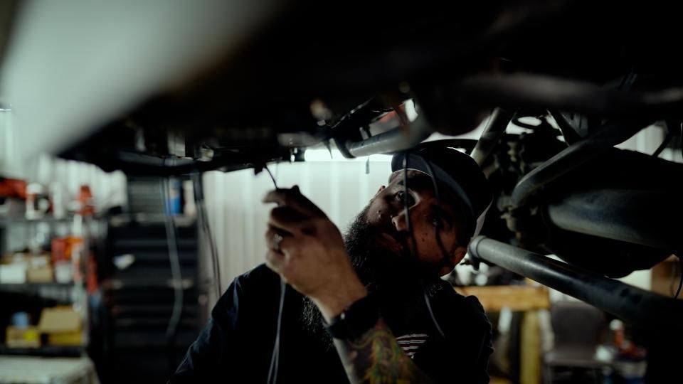 Mechanic inspecting the underside of a vehicle in a garage, using a tool under the chassis