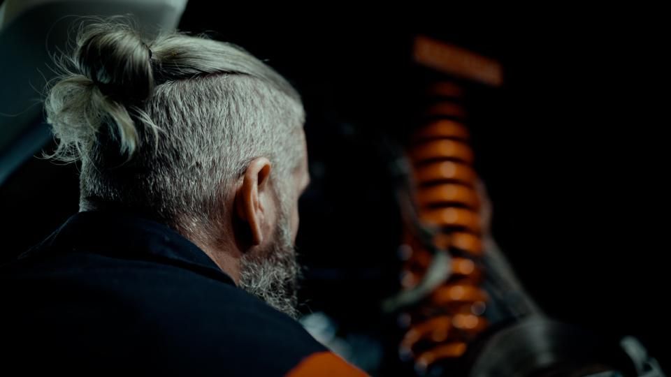 Person seen from behind with gray hair in a bun, facing a glowing orange spiral tower at night