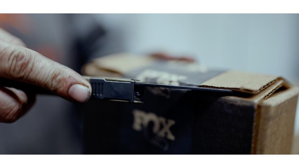 Hand placing a USB drive into the side of a black box on a tabletop