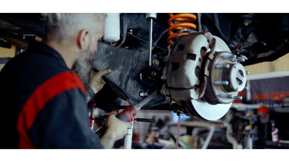 Mechanic inspecting a car’s brake assembly and suspension in an auto repair shop