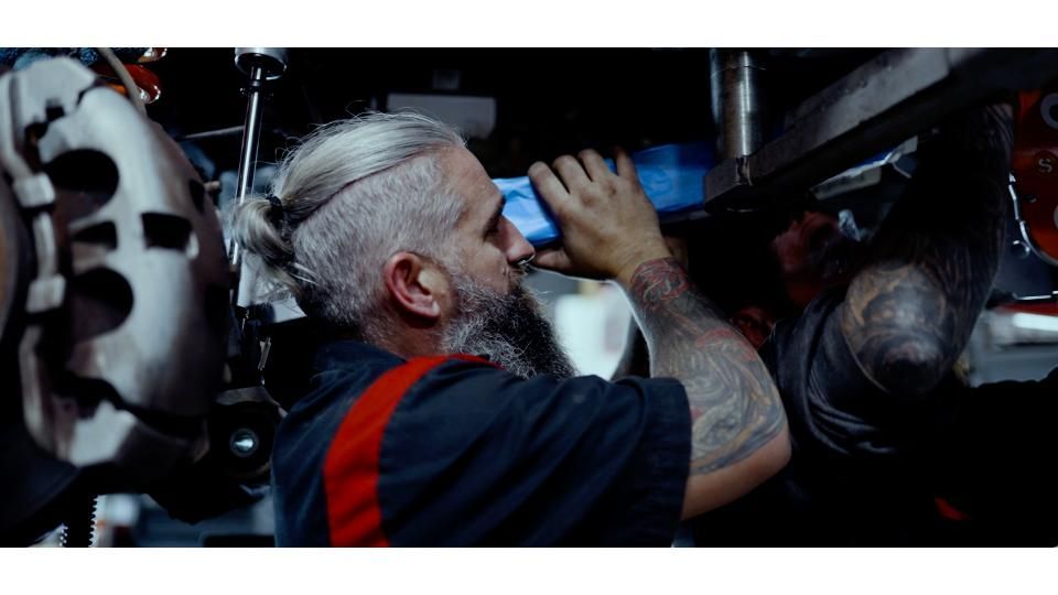 Man in navy shirt using a flashlight to inspect machinery in a dim industrial setting