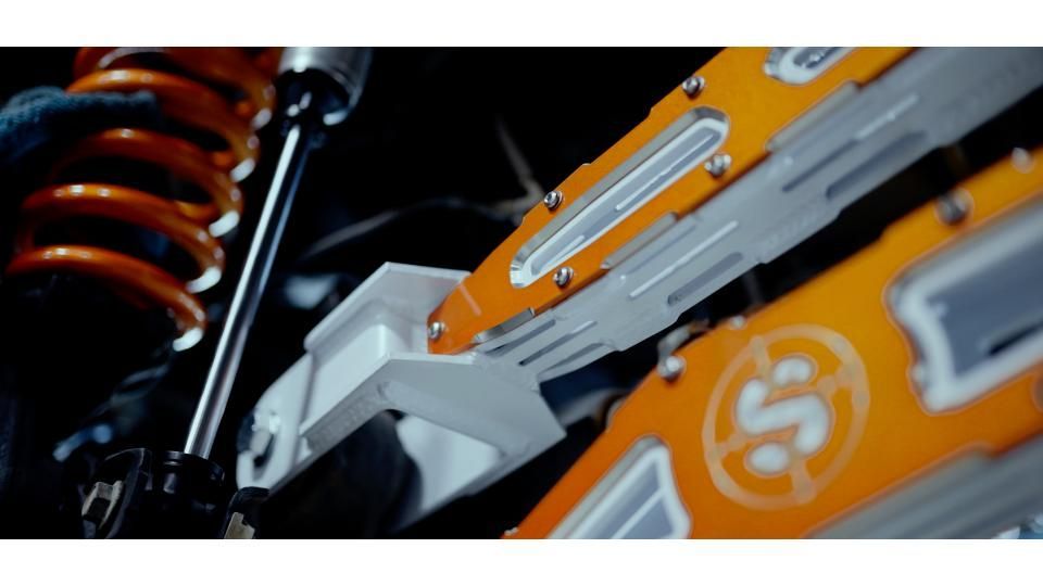 Close-up of an orange-and-white robot arm with mechanical parts and a visible spring.