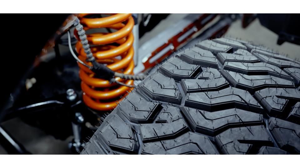 Close-up of a rugged off-road tire and orange suspension coil spring
