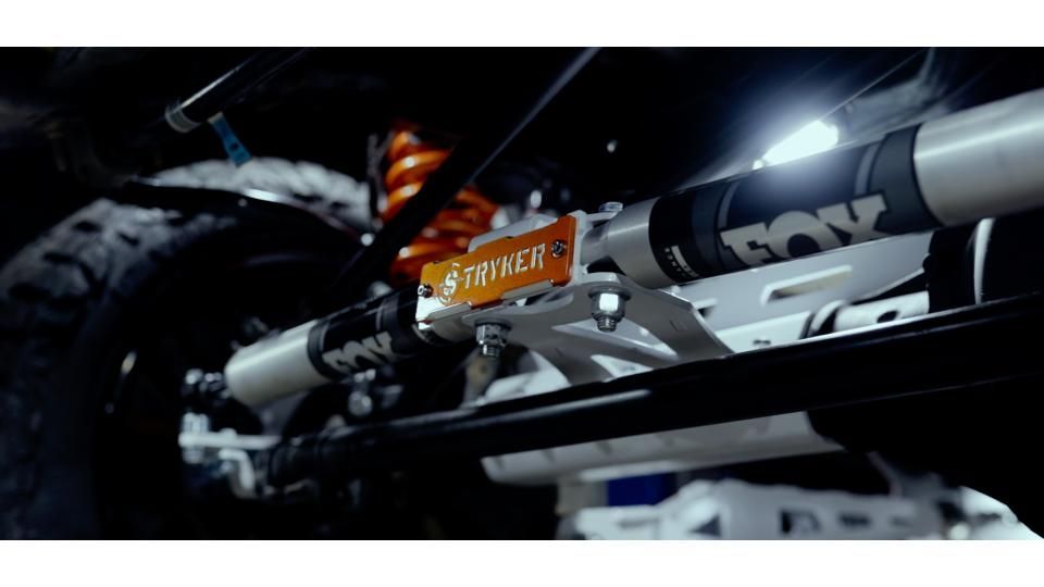 Close-up of a BMX bike frame and handlebars with white and orange decals in a dark studio setting