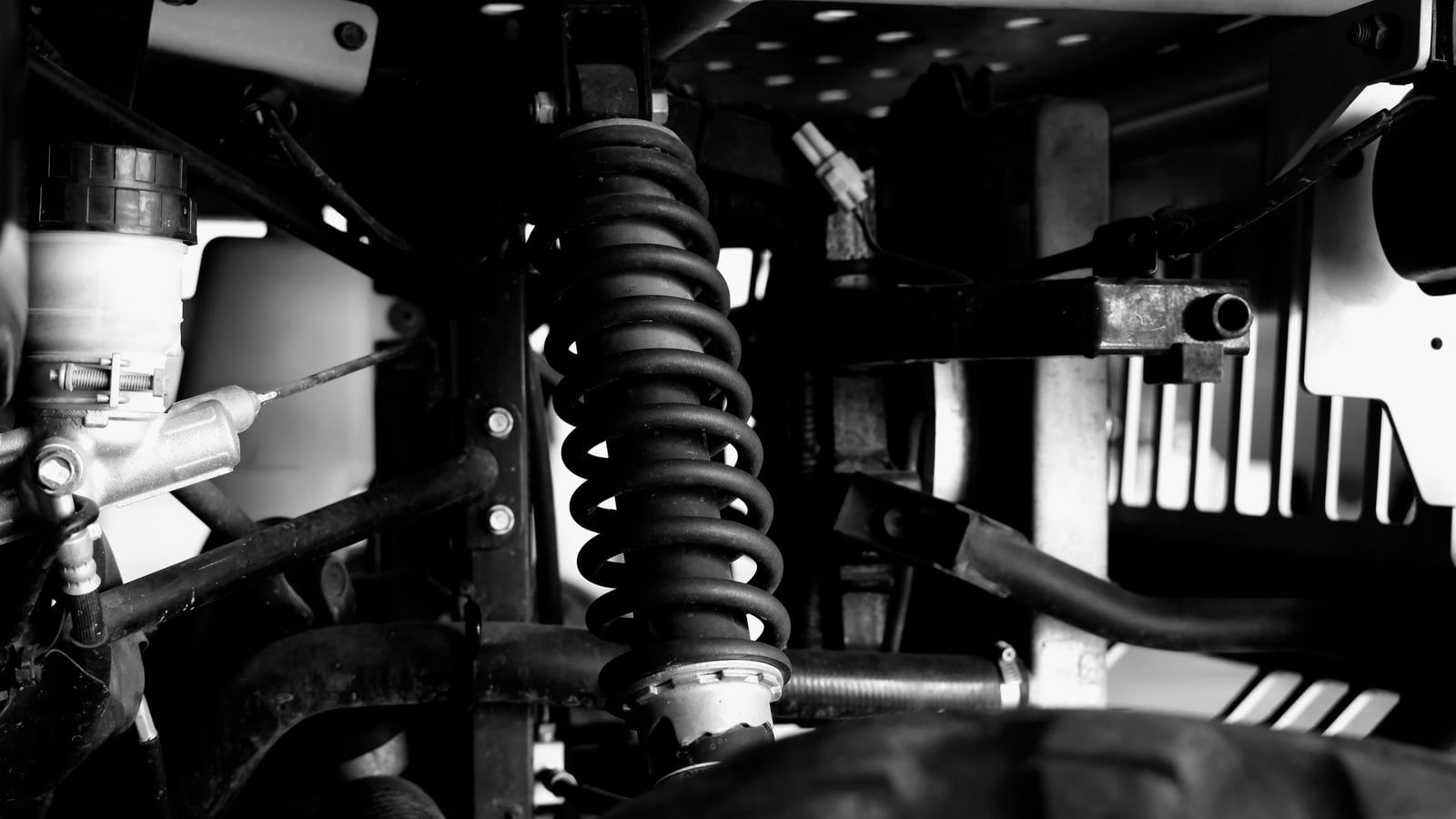 Black Ford F-150 truck with chrome rims on a lift inside a garage with an American flag on the wall.