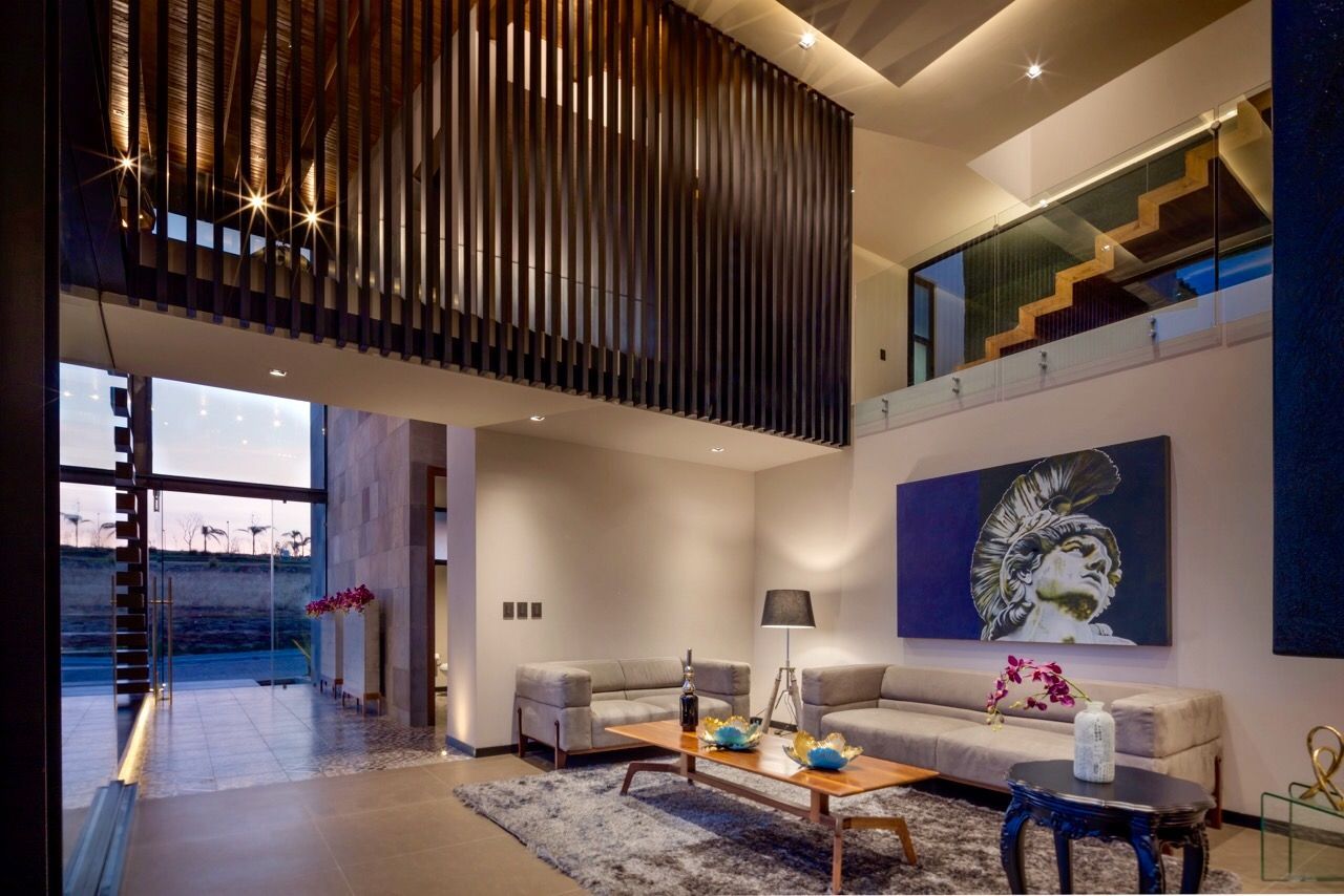 Sala de estar moderna con techo alto, sofá blanco, arte abstracto en la pared y grandes puertas corredizas de vidrio.