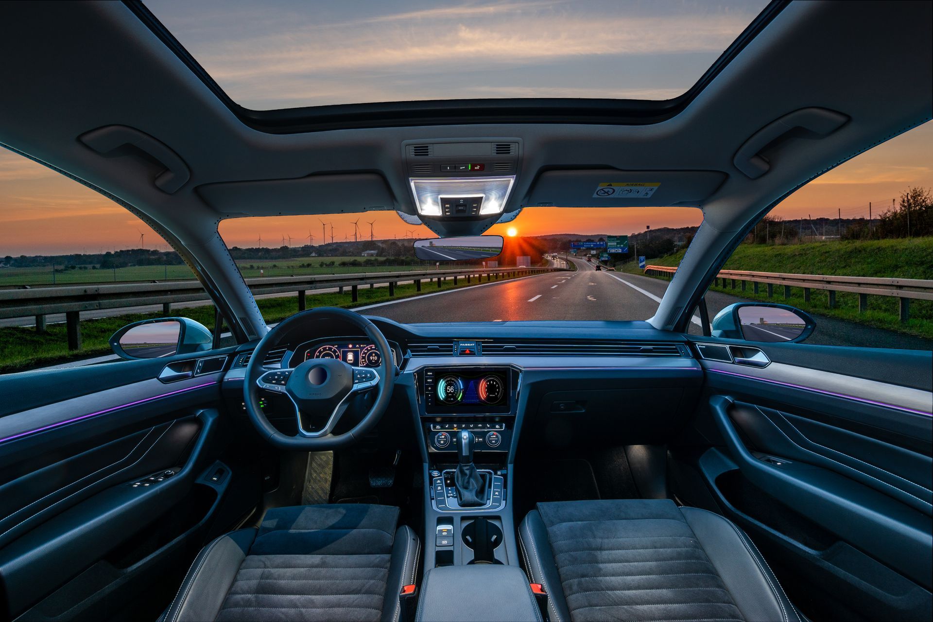 Vue intérieure d'une voiture roulant sur une route au coucher du soleil, avec un toit ouvrant.