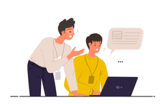 A man is standing next to a man sitting in front of a laptop computer.