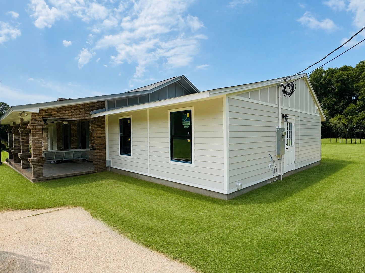 White mobile home with stone porch, green lawn, and blue sky on a sunny day