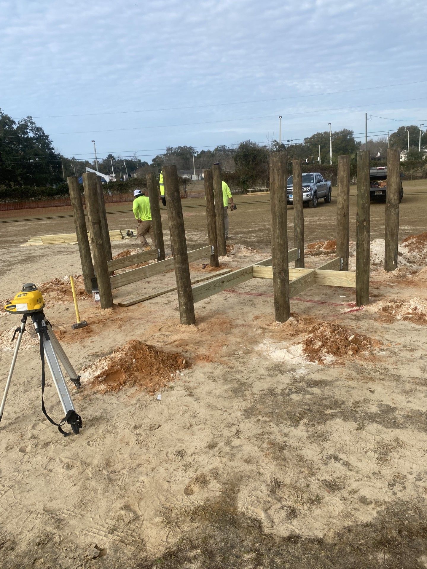 Construction site with concrete columns under construction and workers in neon safety vests