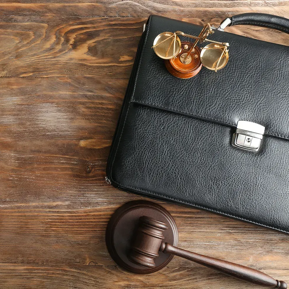 Briefcase, gavel, and small scales on a wooden desk