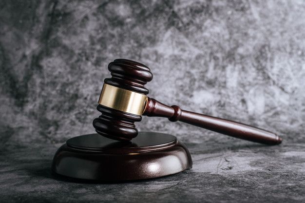 Gavel resting on a wooden sound block against a gray backdrop