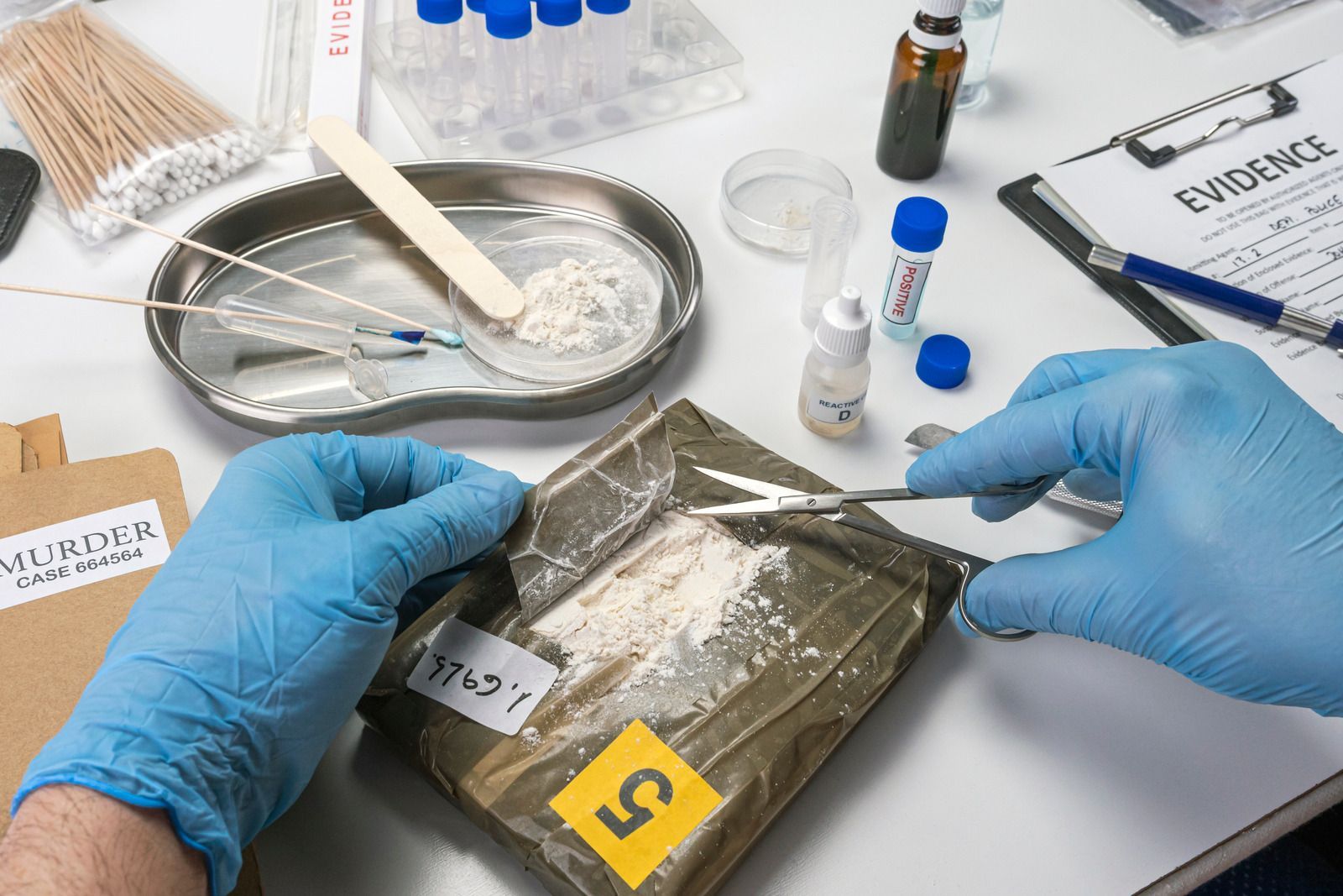Gloved hands inspect a sealed evidence bag on a forensic lab table with tools and samples nearby