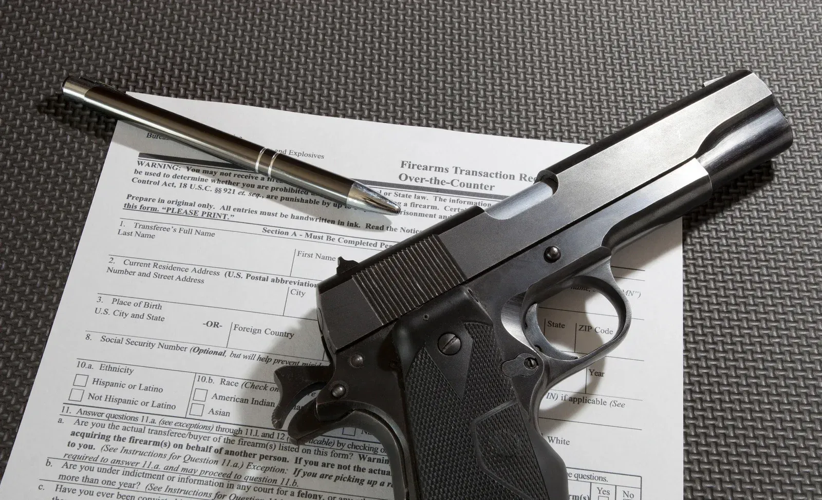 Handgun and pen lying on a document-covered surface