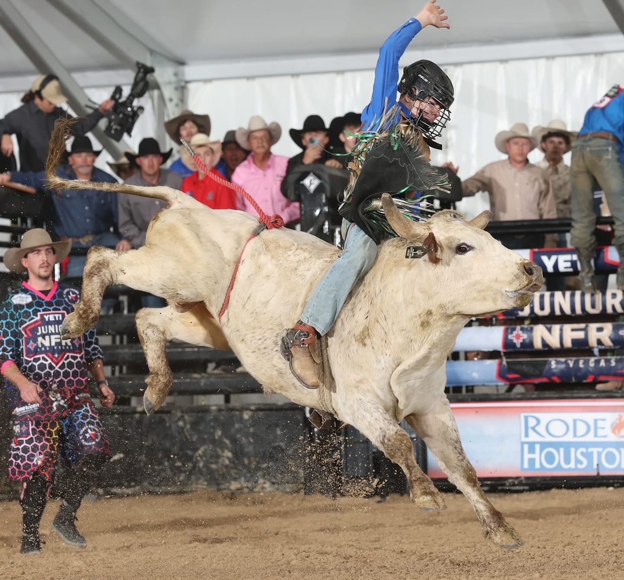 A cowboy on a bucking bull at a rodeo in Houston; the bull leaps, rider with arm raised.