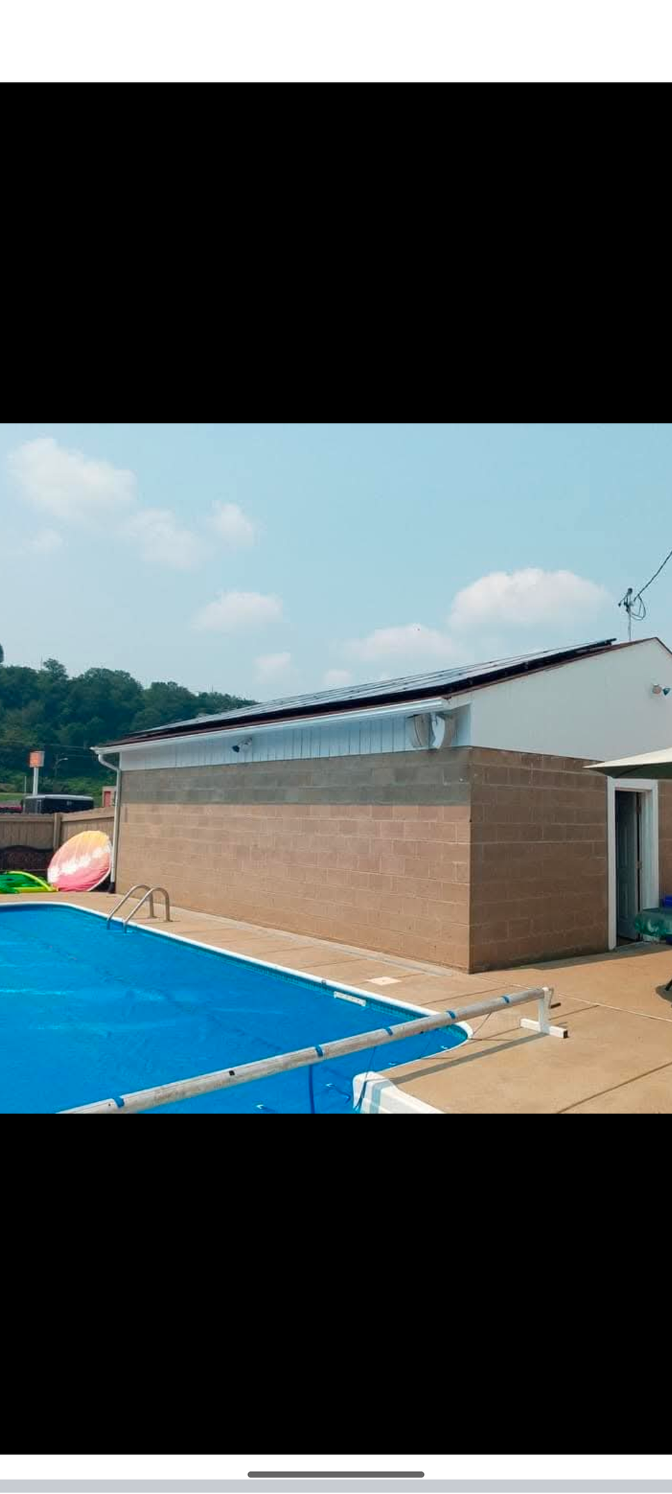 A swimming pool with a blue cover and a building in the background.