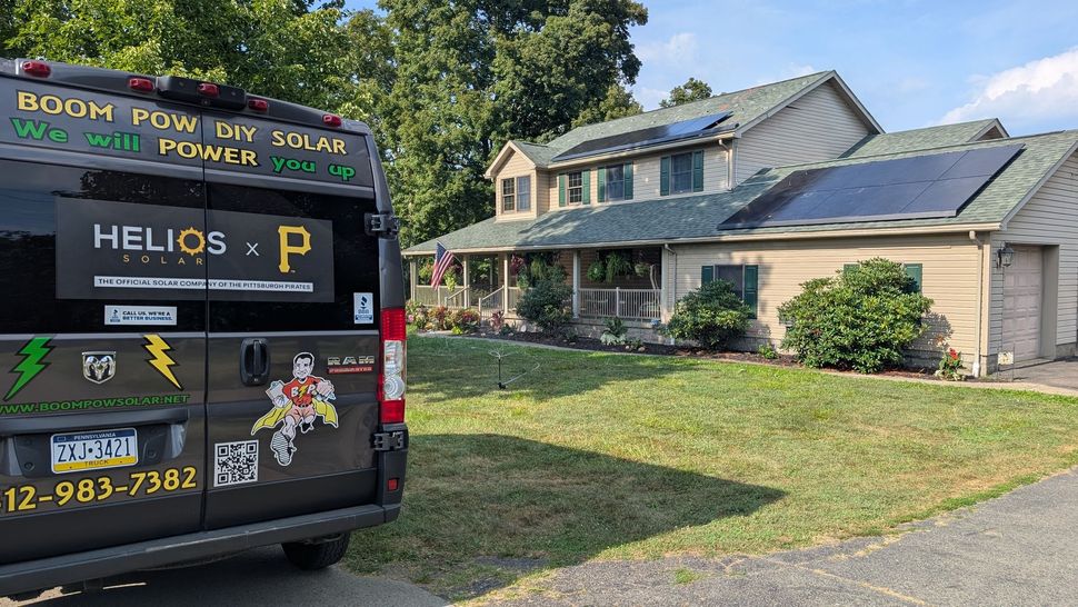 A black van parked in front of a two-story house.